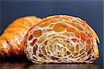 close-up of two croissants, one cut in half with inside texture visible, delicious french pastry