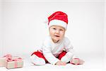 Adorable young baby boy wearing a Santa hat opening Christmas presents