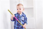 adorable toddler with blue eyes helping with chores, sweeping the floor at home