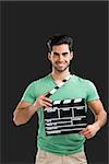Portrait of handsome young man holding a clapboard, isolated on gray background