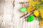 Easter eggs top view spring yellow flowers branch mimosa and willow on old wooden board rustic style, place for text
