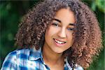 Outdoor portrait of beautiful happy mixed race African American girl teenager female child smiling with perfect teeth