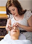 Photo of a beautician plucking the eyebrows of a young woman in a spa.