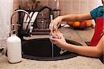 Washing the dishes - child hands cleaning a glass with sponge and foamy detergent at the kitchen sink, shallow depth