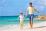 happy family of two, father and son, running and enjoying summer vacation together at perfect caribbean beach