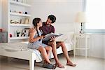 Father And Daughter Sitting On Bed Reading Book Together