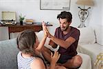 Father And Daughter Playing Clapping Game Sitting On Sofa