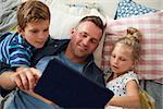 Father And Children Lying On Floor Using Digital Tablet