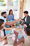 Friends serving each other at a dinner party on a patio