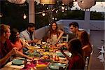 Friends talking at a dinner party on a patio, elevated view