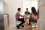 View from doorway of teenagers talking at lunch in a kitchen