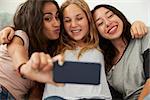 Three teenage girls taking selfie at home, focus on girls