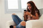 Teenage girl text messaging with smartphone at home