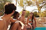 Group Of Friends On Vacation Relaxing Next To Outdoor Pool