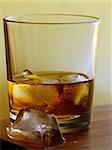 glass of whiskey with ice on a gold background