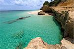 view of rocky rugged shore with white sand beach and turquoise lagoon at anguilla island