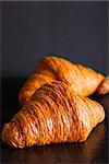 two crunchy delicious croissants at black background