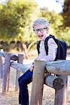 smiling little schoolboy with backpack being playful in the park ready for school year, back to school concept