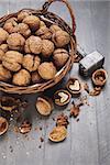 Walnut in wicker basket on old wooden board rustic style with nutshell top view