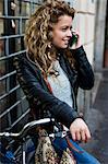 Woman with bicycle in street making telephone call on mobile phone