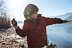 Young boy beside lake, throwing stone into lake