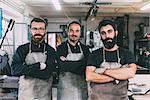 Portrait of three male metalworkers in forge workshop