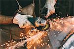 Hands of metalworker grinding copper in forge workshop