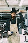 Portrait of metalworker holding welding torch in forge workshop