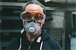 Portrait of metalworker in dust mask and safety goggles in forge workshop