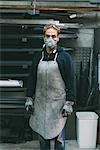 Portrait of metalworker in dust mask in forge workshop