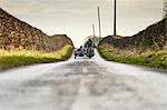 Rear view of senior man and grandson riding motorcycle and sidecar on rural road