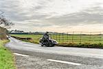 Senior man and grandson riding motorcycle and sidecar on rural road