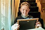 Boy sitting on stairs gazing at photograph frame