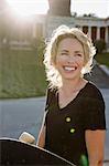 Female skateboarder carrying skateboard in sunlit park