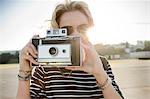 Mid adult woman taking photographs on vintage camera