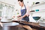 Young woman shaping dough at kitchen counter