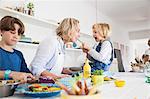 Girl feeding mother asparagus at kitchen table