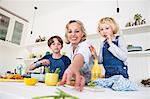 Mature woman reaching for asparagus at kitchen table with son and daughter