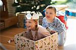 Boy pushing sister in cardboard box at christmas