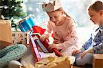 Girl and brother on living room floor gazing at toy guitar christmas gift