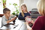 Grandmother and grandchildren playing cards at home