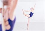 Mirror image of young female ballet dancer en pointe in dance studio