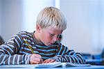 Boy in classroom, sitting at desk, doing classwork