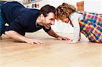 Mature man crawling head to head with daughter on kitchen floor