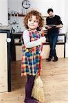 Mature man in kitchen with daughter sweeping floor