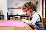 Girl drawing on pink paper at table