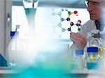 Researcher using a molecular model to understand a chemical formula in a laboratory