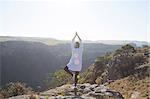 Woman standing on mountain top, in yoga position, rear view, South Africa