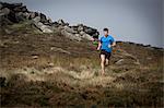 Male runner running down from Stanage Edge, Peak District, Derbyshire, UK