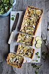 Savoury blue cheese and courgette tart topped with walnuts, sliced